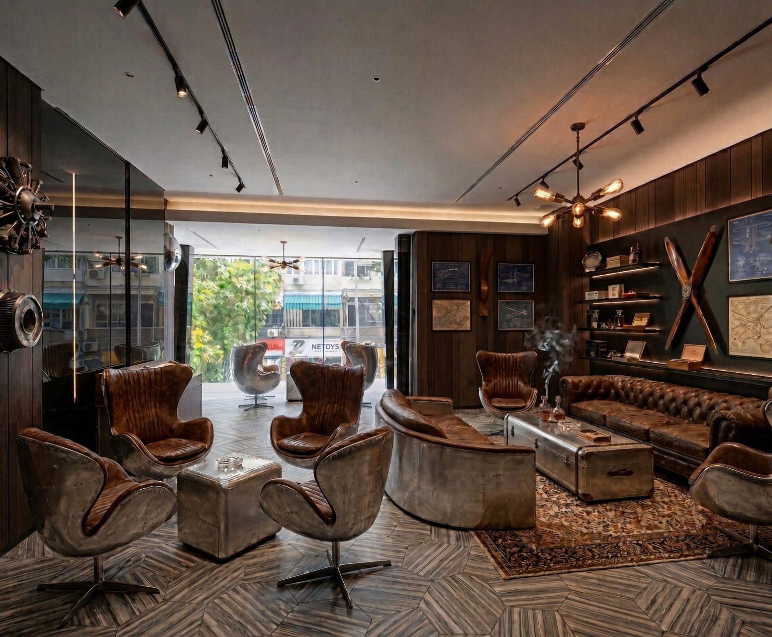 The real Aviator interior: floor-to-ceiling glass onto a leafy District 3 street with daylight pouring in from the left, deep shadow falling across dark walnut, cognac leather and brushed aluminium on the right